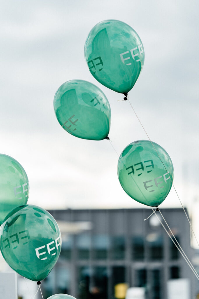 Grüne Luftballons mit EEF Logos steigen in den Himmel.